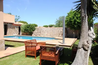a backyard with a pool and two chairs and a tree at Villa Solea in Chiclana de la Frontera
