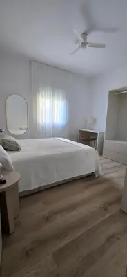 a bedroom with a white bed and a ceiling fan at Apartamento Arbolí in Cádiz