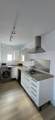 a kitchen with white cabinets and a counter top at Apartamento Arbolí in Cádiz