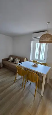 a living room with a table and chairs and a couch at Apartamento Arbolí in Cádiz