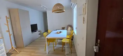 a dining room with a white table and yellow chairs at Apartamento Arbolí in Cádiz
