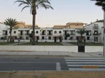 an empty street with palm trees and white buildings at CALLE YERBABUENA 5 in Sanlúcar de Barrameda