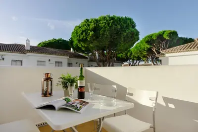 a white table with a bottle of wine and a book at Pinar 12 in Chiclana de la Frontera