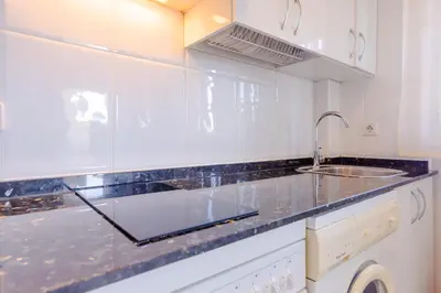 a white kitchen with a sink and a counter at Pinar 12 in Chiclana de la Frontera
