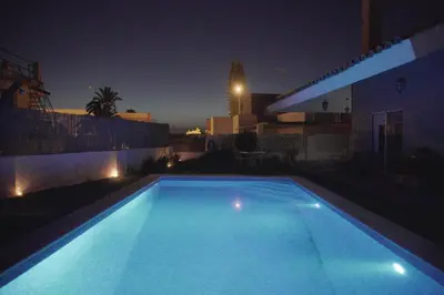 a blue swimming pool at night with a building at Casa/Chalet Doñana in Sanlúcar de Barrameda