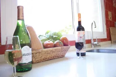 two bottles of wine and a basket of apples on a kitchen counter at Casa/Chalet Doñana in Sanlúcar de Barrameda