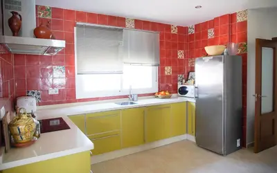 a kitchen with yellow and red tiled walls and a refrigerator at Casa/Chalet Doñana in Sanlúcar de Barrameda
