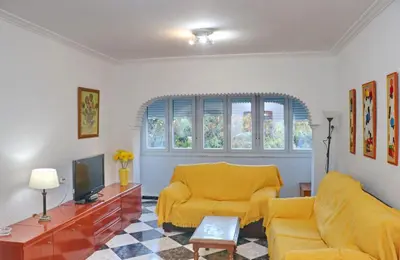 a living room with a yellow couch and a tv at Apartamento Plaza la Fuente in Cádiz