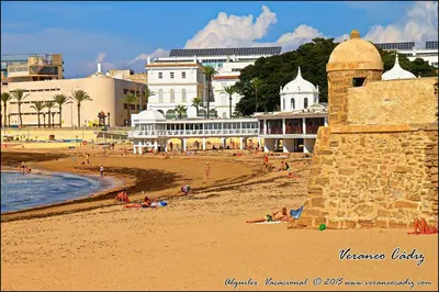 a beach with people laying on the sand and buildings at Apartamento Plaza la Fuente in Cádiz