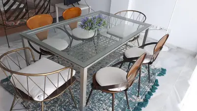 a glass table with chairs and a vase with flowers at Vivienda Vistahermosa Playa in El Puerto de Santa María