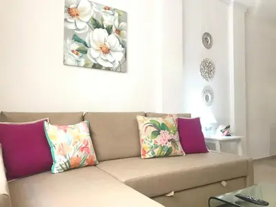 a living room with a brown couch with colorful pillows at Apartamento !!VIVE JEREZ!! in Jerez de la Frontera