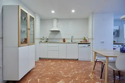 a kitchen with white cabinets and a wooden table at corazón de jerez edificio de 1861 in Jerez de la Frontera