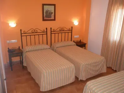 two beds in a hotel room with orange walls at Hotel Cortijo Los Gallos in Chiclana de la Frontera