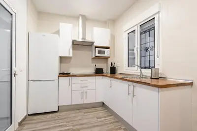 a white kitchen with a sink and a refrigerator at Encantador loft Teatro Falla in Cádiz