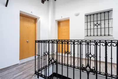 a staircase with a wrought iron railing and a door at Encantador loft Teatro Falla in Cádiz