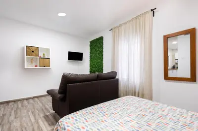 a bedroom with a bed and a chair and a mirror at Encantador loft Teatro Falla in Cádiz