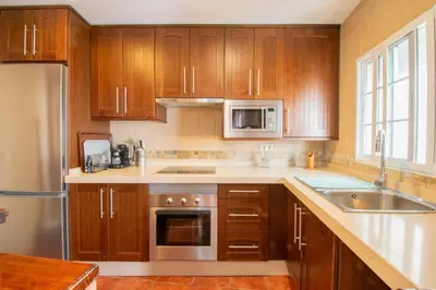 a kitchen with wooden cabinets and stainless steel appliances at Casa Rural Napoleón in Medina Sidonia