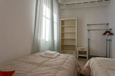 a white bedroom with a bed and a window at Atico del ROMANTICO Gaditano by Cadiz4Rentals in Cádiz