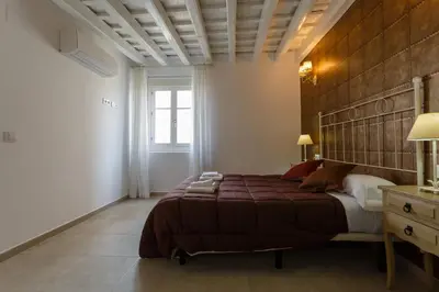a bedroom with a large bed with a wooden headboard at Atico del ROMANTICO Gaditano by Cadiz4Rentals in Cádiz