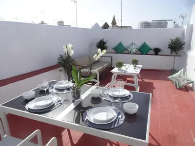 a white table with plates and glasses on a balcony at Atico Terraza Cadiz Centro Ascensor Playa de la Caleta in Cádiz