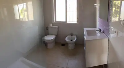 a white bathroom with a toilet and a sink at Chalet en Conil, descansa y disfruta BBQ AIRE PISCINA PARKING in Conil de la Frontera