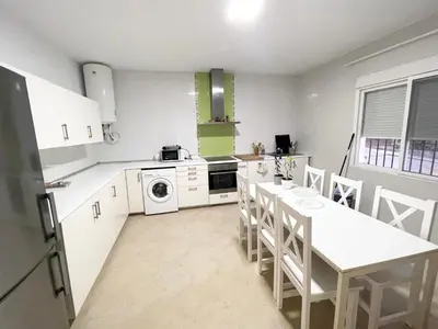 a kitchen with white appliances and a table and chairs at Chalet en Conil, descansa y disfruta BBQ AIRE PISCINA PARKING in Conil de la Frontera
