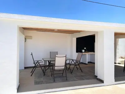 a patio with a table and chairs and a television at Chalet en Conil, descansa y disfruta BBQ AIRE PISCINA PARKING in Conil de la Frontera