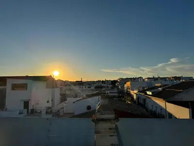 a view of a city with the sun setting at El Rinconcito - apartamento palacete rehabilitado in El Puerto de Santa María