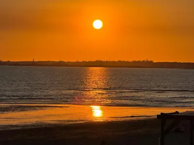 a sunset on the beach with the sun setting at El Rinconcito - apartamento palacete rehabilitado in El Puerto de Santa María