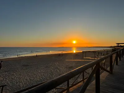 a sunset on a beach with a wooden boardwalk at El Rinconcito - apartamento palacete rehabilitado in El Puerto de Santa María