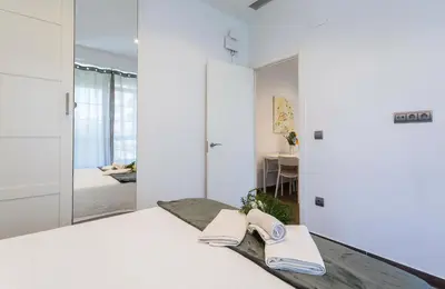 a bedroom with a bed with white walls and a mirror at San Jose 2 baños in Cádiz