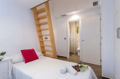 a bedroom with a white bed with a red pillow at San Jose 2 baños in Cádiz