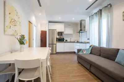 a living room with a couch and a table and a kitchen at San Jose 2 baños in Cádiz