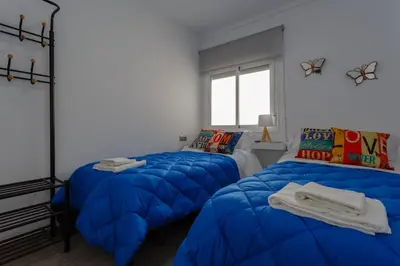 two beds in a room with blue comforters at El TESORO de la Caleta by Cadiz4Rentals in Cádiz