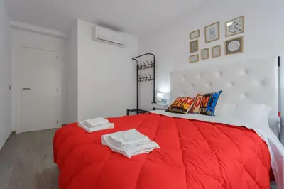 a red bed in a white room with towels on it at El TESORO de la Caleta by Cadiz4Rentals in Cádiz