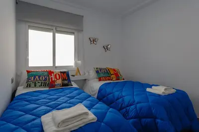 a bedroom with a blue comforter and a bed at El TESORO de la Caleta by Cadiz4Rentals in Cádiz