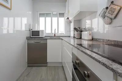a white kitchen with a sink and a microwave at El TESORO de la Caleta by Cadiz4Rentals in Cádiz