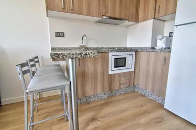 a kitchen with a counter and a table and chairs at Apartamentos Arenal in Jerez de la Frontera