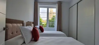 a bedroom with two beds with red pillows and a window at Apartamentos Arenal in Jerez de la Frontera