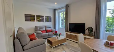 a living room with a couch and a tv and a table at Apartamentos Arenal in Jerez de la Frontera
