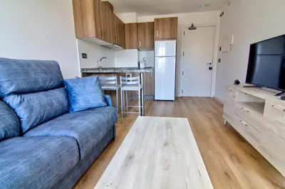 a living room with a couch and a kitchen at Apartamentos Arenal in Jerez de la Frontera