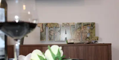 a glass of wine next to some art on a wall at GATU PREMIUM Villa Aramburu, 