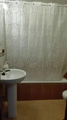 a bathroom with a sink and a shower curtain at Duplex Calle Padre Lerchundi con Parking y wifi in Chipiona