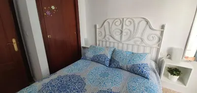 a bed with a blue comforter and two pillows at Duplex Calle Padre Lerchundi con Parking y wifi in Chipiona