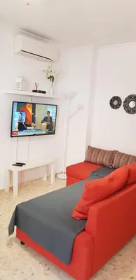 a living room with a red couch and a flat screen tv at Duplex Calle Padre Lerchundi con Parking y wifi in Chipiona