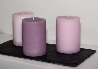 three purple and pink candles sitting on a black board at La Casa del Arte in Cádiz