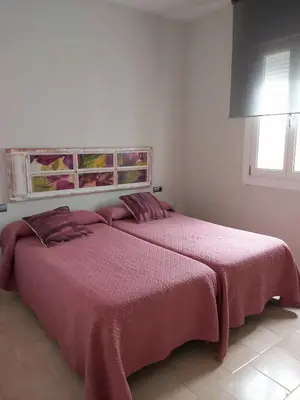 a bedroom with two beds with pink sheets and a window at La Casa del Arte in Cádiz