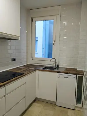 a white kitchen with a sink and a window at La Casa del Arte in Cádiz