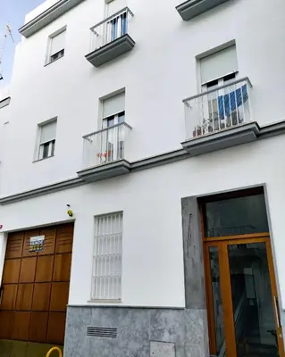 a white building with a wooden door and windows at La Casa del Arte in Cádiz
