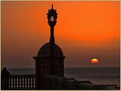 a clock tower with the sunset in the background at La Casa del Arte in Cádiz